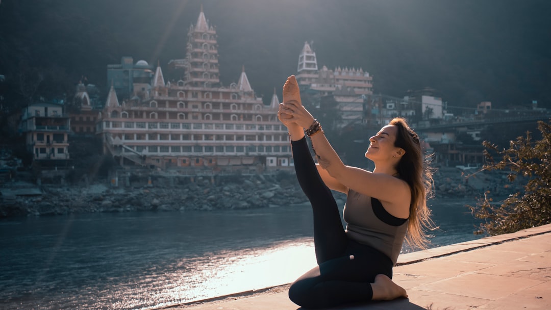 Student practising yoga pose on a quiet clifftop at sunrise — the kind of stillness taught at Anand Yog Amrit Yoga Center, Punjabi Bagh